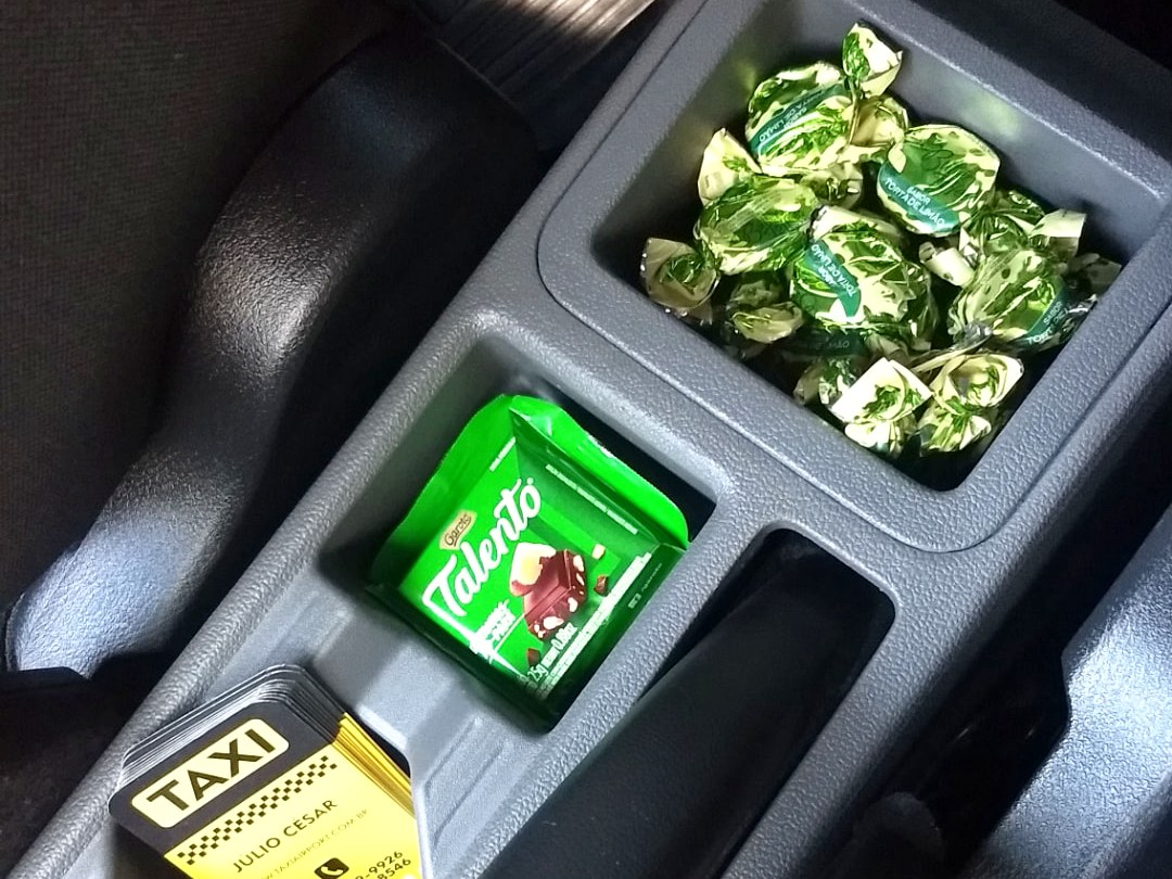 Cortesia no console do carro: balas, chocolate e cartões da Minas Táxi